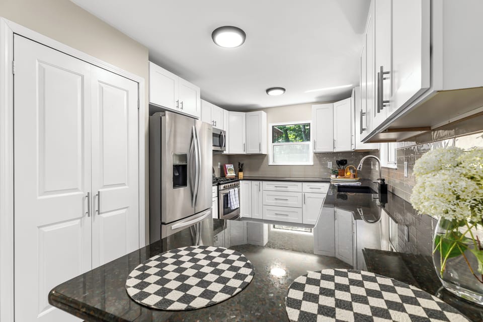 The kitchen is equipped with a microwave, stove, oven, toaster, coffee bar, refrigerator/freezer, dishwasher, sink with hot and cold water, as well as trays, glasses, silverware, and a selection of pots and pans.