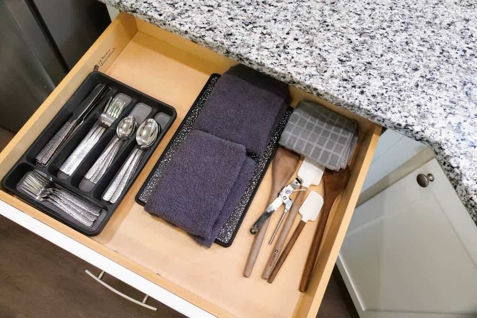 - Organized kitchen drawer with cutlery utensils and towels   - Silverware wooden tools and linens neatly arranged inside   - Fully stocked for cooking baking and everyday convenience  