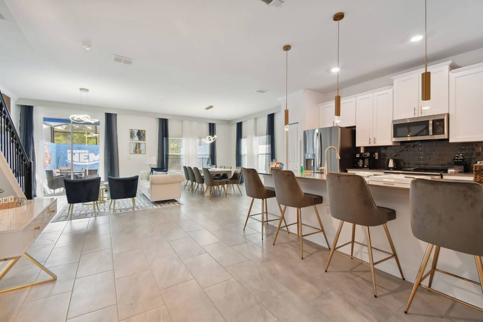 This bright, modern kitchen boasts sleek white cabinets and dark countertops for a stunning contrast. Enjoy meals at the stylish bar with cozy stools or gather in the spacious dining area filled with natural light.