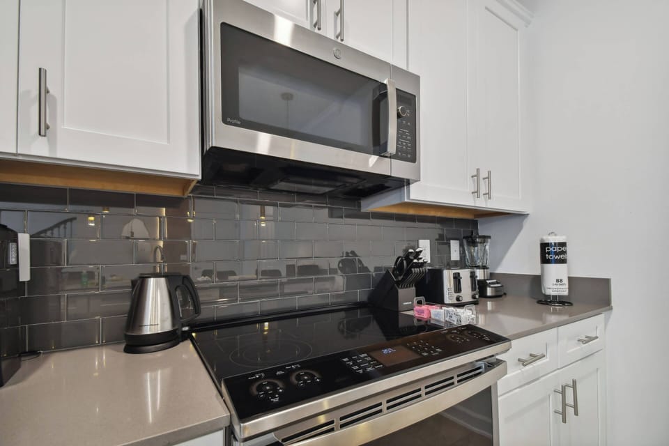 Step into this stylish kitchen featuring sleek stainless steel appliances and a chic tile backsplash that adds a touch of sophistication. The spacious countertops invite culinary creativity, making meal prep a joyful experience.