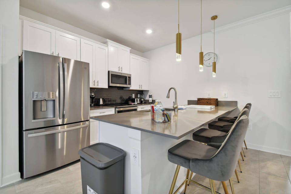 This sleek kitchen boasts a spacious island with stylish bar seating, ideal for casual meals. The stainless steel appliances and modern fixtures enhance the bright atmosphere, inviting you to create your favorite dishes.