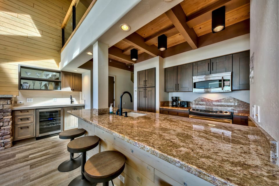 You'll love preparing meals in this stunning open-concept kitchen featuring granite countertops, modern appliances, and elegant exposed beam ceiling.