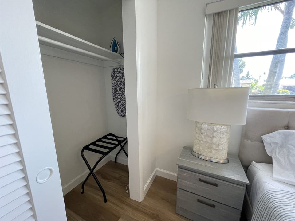 The master bedroom closet offers a convenient luggage rack, iron, and ironing board for your stay. Plus, enjoy a second luggage rack in the second guest bedroom, ensuring you have everything you need for a comfortable and organized visit