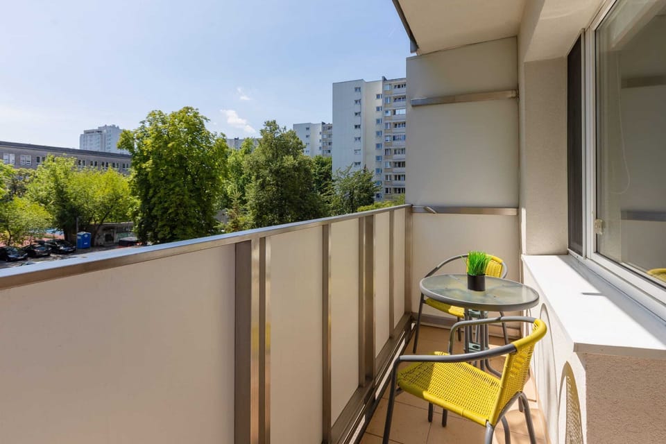 A balcony with seating and a view of lush greenery, perfect for morning coffee.

