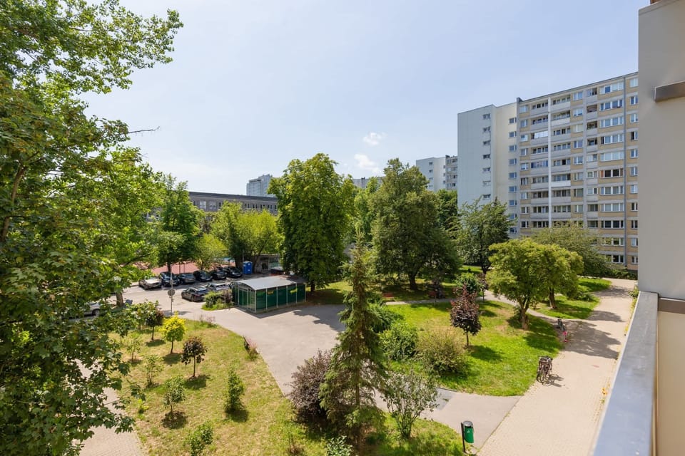 A scenic view of the neighborhood with green trees and residential buildings.

