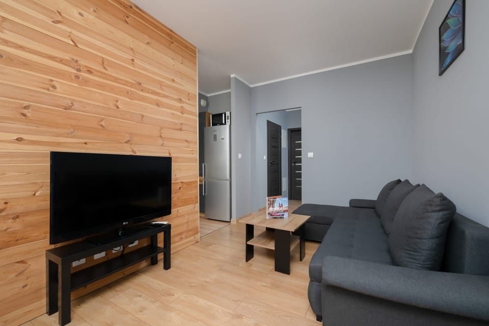 Another angle of the living room showcasing the TV area and wooden panel walls.


