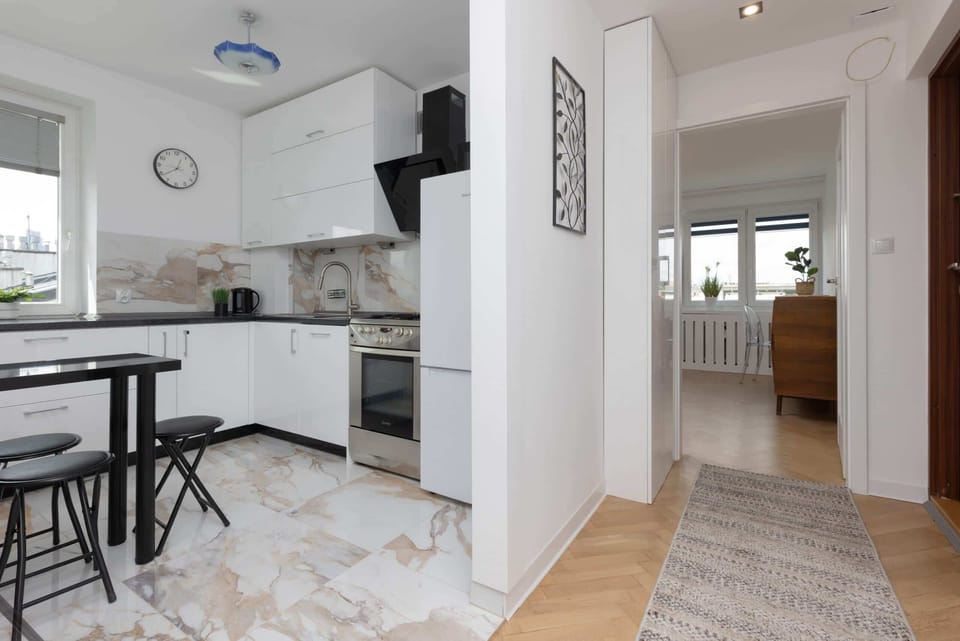 A hallway view leading into a functional, well-organized kitchen with bright, clean finishes.

