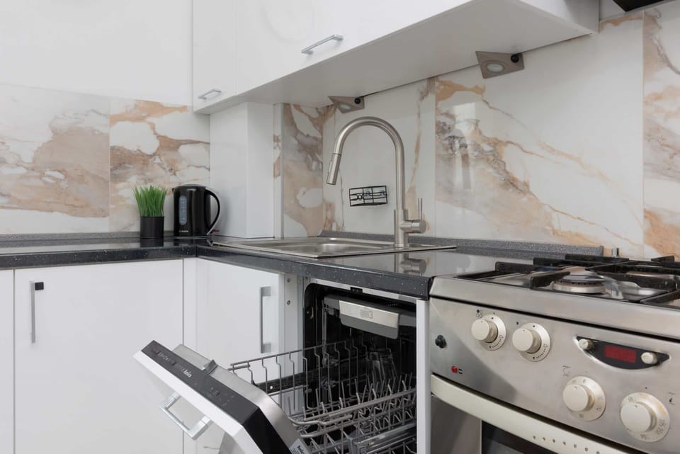 A close-up of the kitchen showcasing marble details, a stainless steel stove, and modern appliances.

