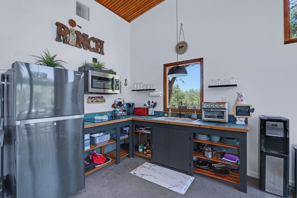 Close up view of the kitchen. It has a refrigerator, microwave, stove top, coffee pot, and small table top oven.