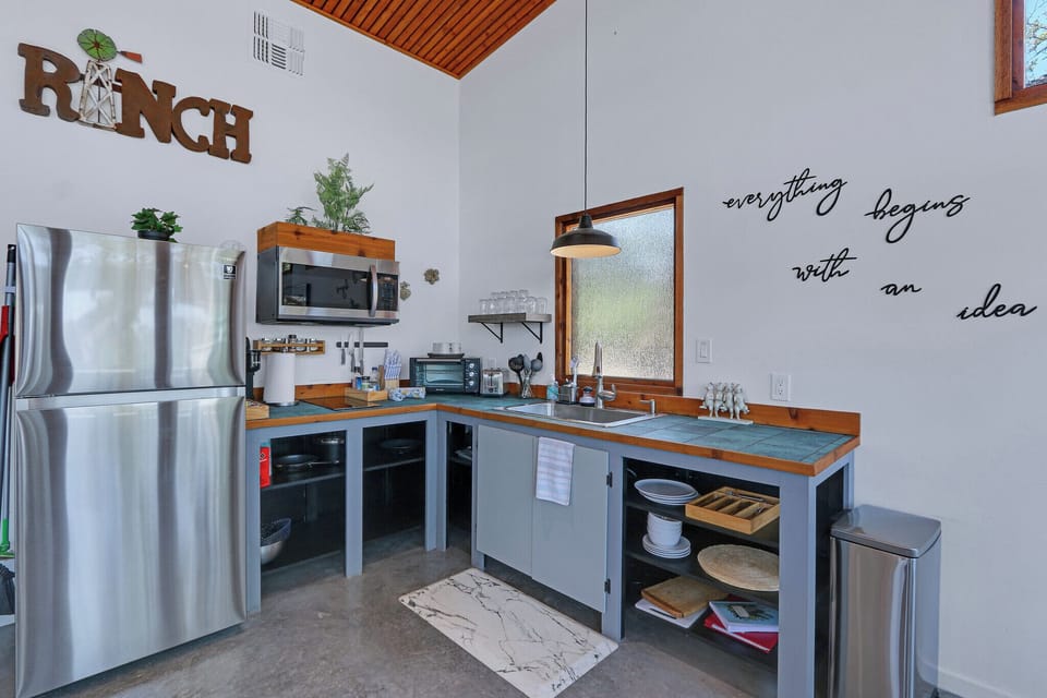 Close up of the kitchen.  The kitchen has refrigerator, range, microwave, coffee pot, and small counter top oven.