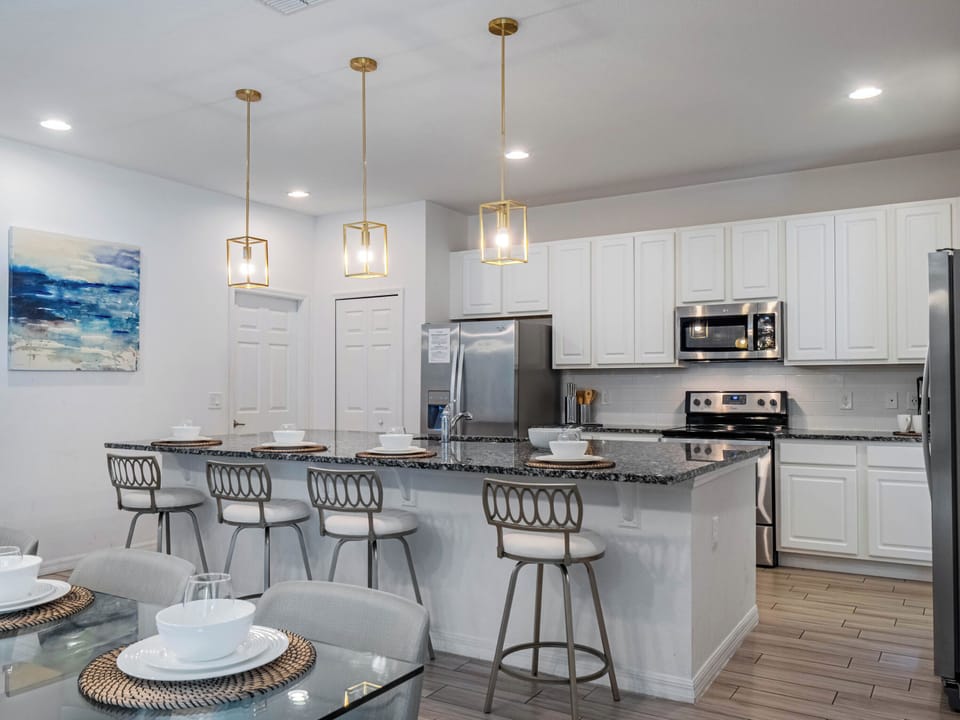 - Bright kitchen with granite island and bar stool seating  
- White cabinetry and stainless steel appliances throughout  
- Open design flows seamlessly into dining and living area