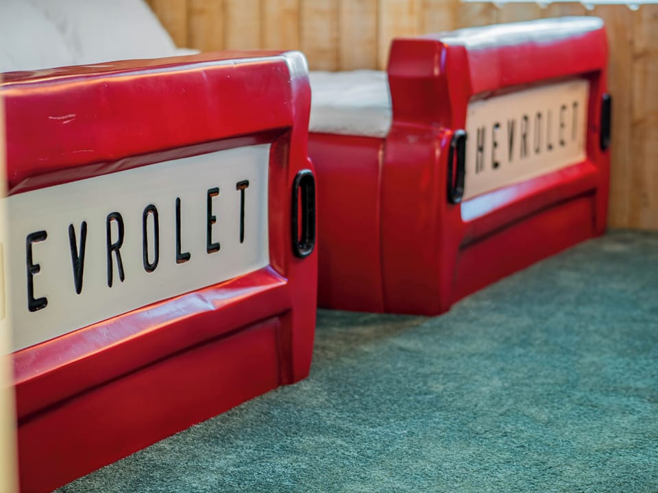 - Chevrolet truck bed frames in kids themed bedroom  
- Playful design brings classic drive-in style to life  
- Unique setup creates a fun family-friendly sleep space