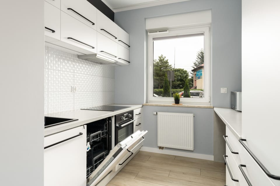 A modern kitchen with white cabinetry, a large window, and high-end appliances.

