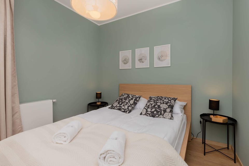 A bedroom with minimalistic decor, featuring a large bed, soft bedding, and framed wall art.

