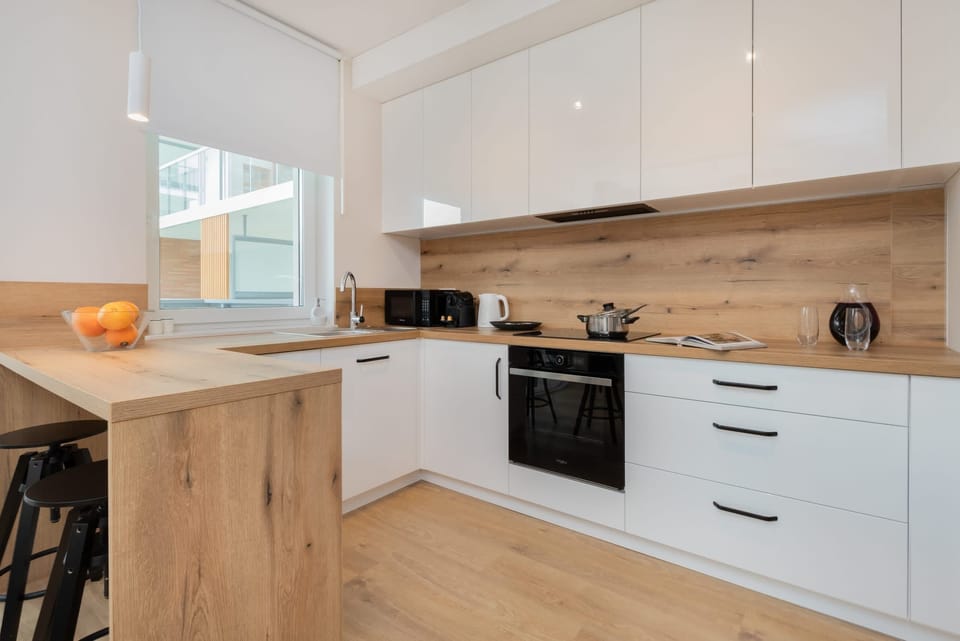 A modern kitchen with white cabinetry, wooden countertops, and stainless steel appliances.

