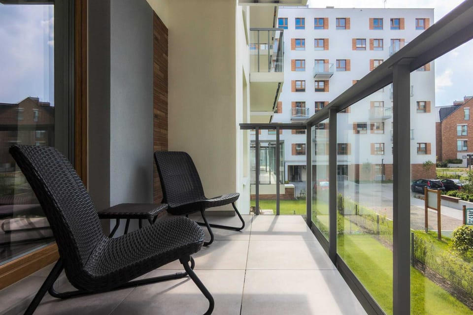 A spacious balcony with outdoor chairs and views of a landscaped residential area.


