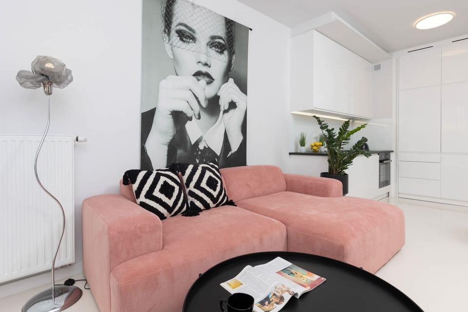 A close-up of the living room highlighting the pink sofa, bold art, and stylish details.

