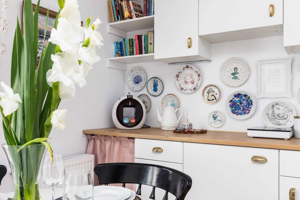 A dining area with natural light, pink curtains, and decorative details enhancing the aesthetic.

