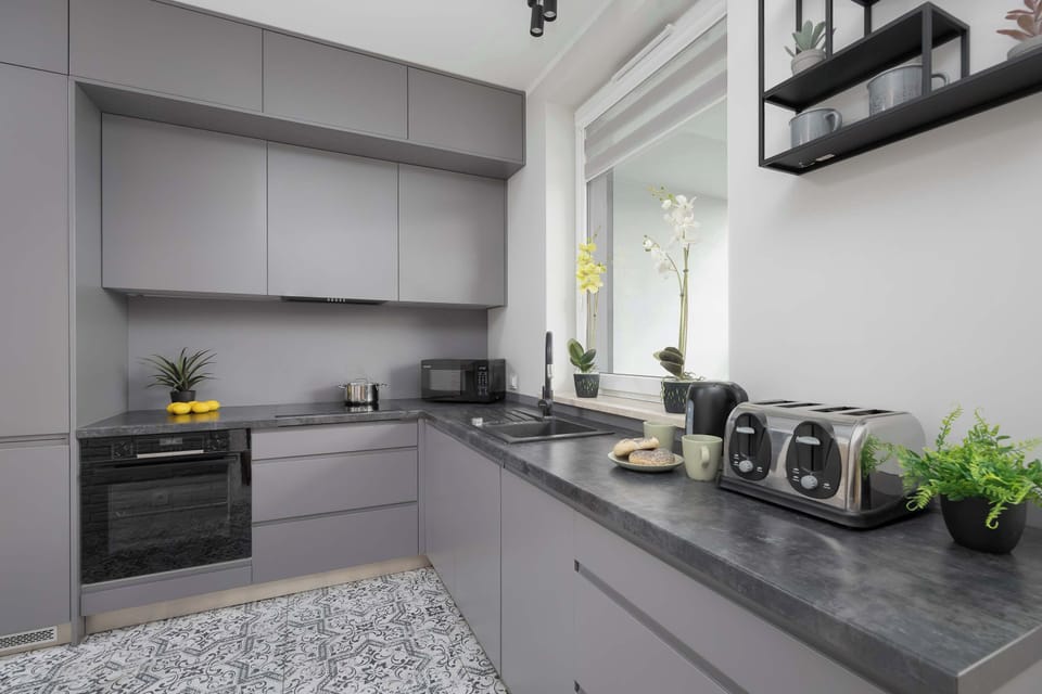 A modern kitchenette with grey cabinets and quality appliances ensures that home-cooked meals can be prepared.