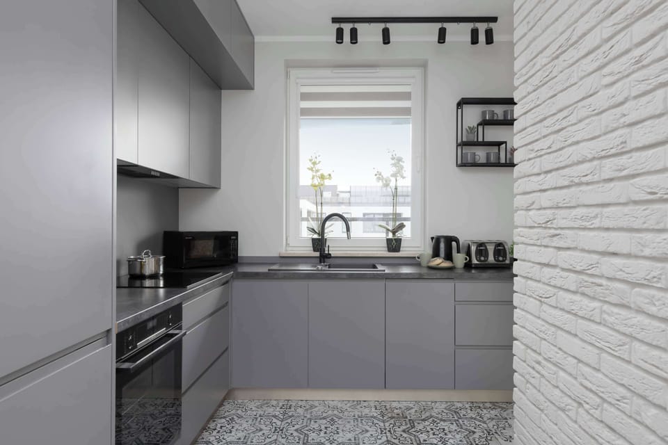 A modern kitchenette with grey cabinets and quality appliances ensures that home-cooked meals can be prepared.