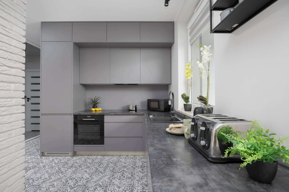 A modern kitchenette with grey cabinets and quality appliances ensures that home-cooked meals can be prepared.
