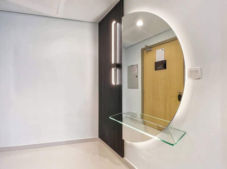Step into sleek simplicity with this modern entryway featuring a circular mirror, ambient lighting, and clean lines. A stylish welcome that sets the tone for a refined urban stay.