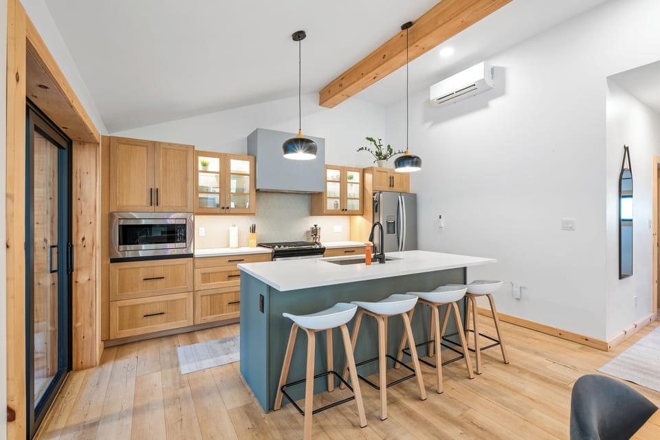 A chef's kitchen with quartz countertops, gas range and fridge with ice maker. 