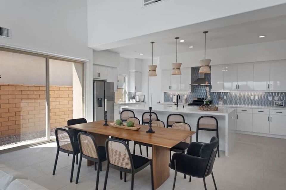 Open dining & kitchen space w/ long table, island seating & sleek modern finishes