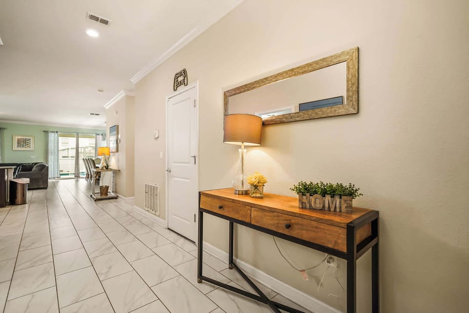 Welcoming private entryway with a rustic wood console, framed mirror, and views toward the bright living and dining areas.