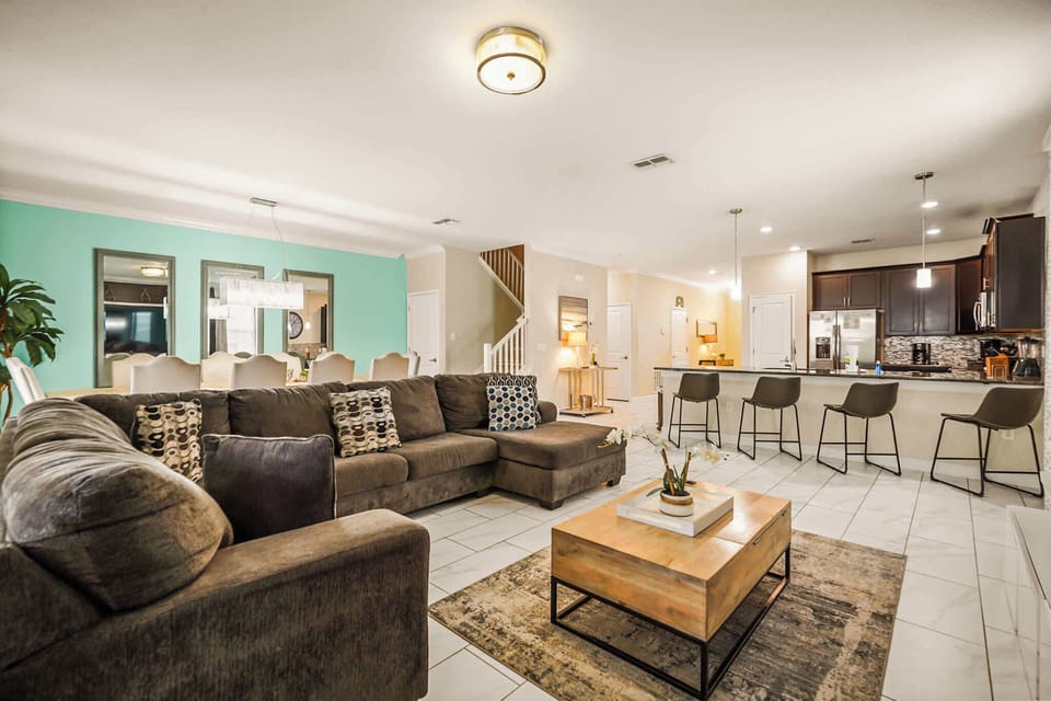 Relax in this expansive living area with a cozy sectional, stylish dining, and modern kitchen—ideal for gatherings and family fun.