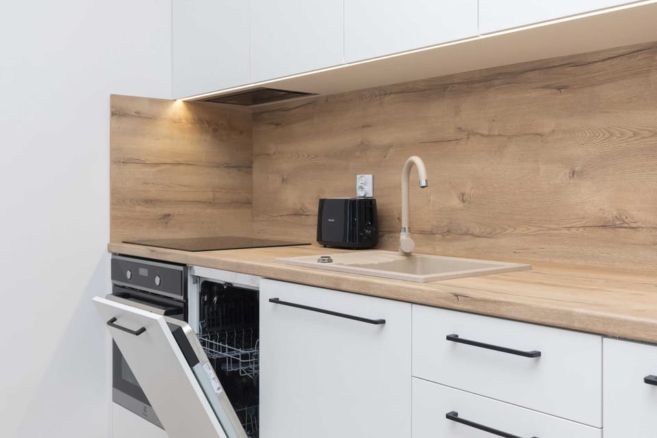 A compact yet fully equipped kitchen with white cabinetry, wooden countertops, and modern appliances, perfect for preparing meals.

