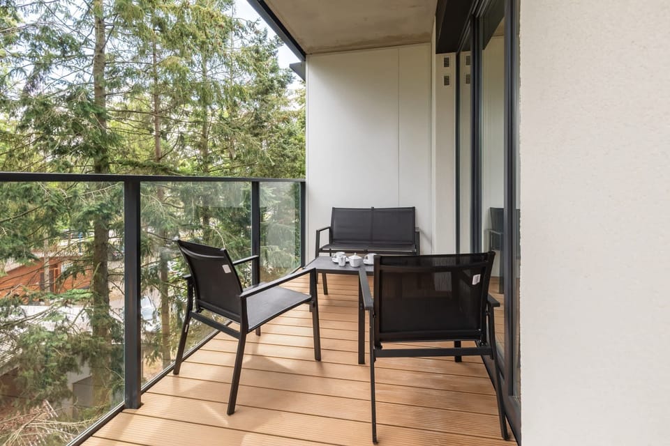 A balcony featuring a small table, two chairs, and a glass railing, offering a private outdoor space with scenic views.

