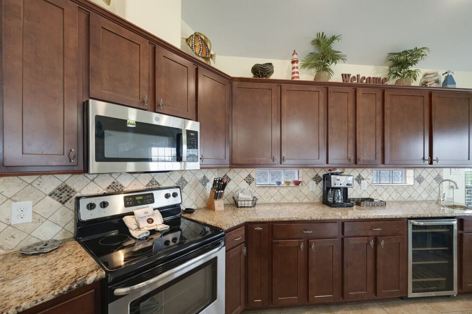 Fully equipped kitchen featuring stainless steel appliances, ample cabinetry, and coastal-inspired finishes.