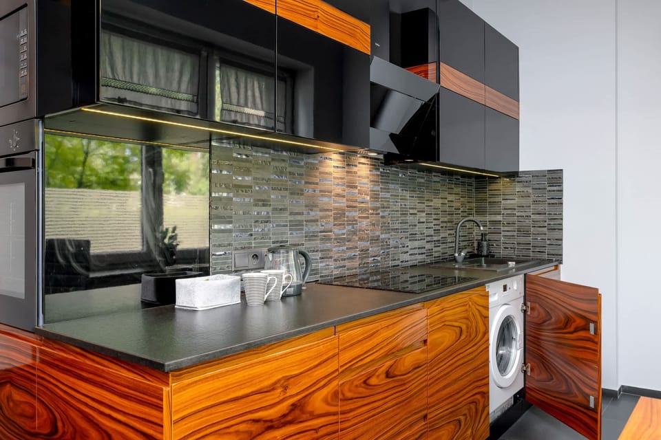Functional kitchenette with sleek and modern furnishings. A washing machine is concealed in the cupboard.