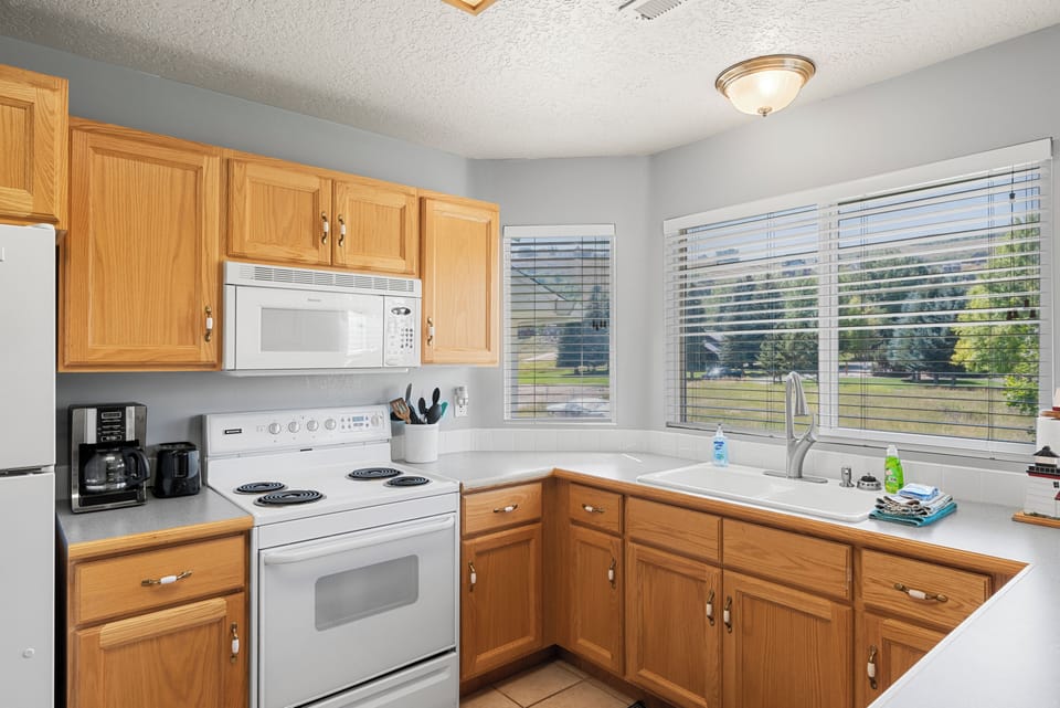 Kitchen - fridge/freezer, electric stove, fully stocked with dishes and coffee maker.