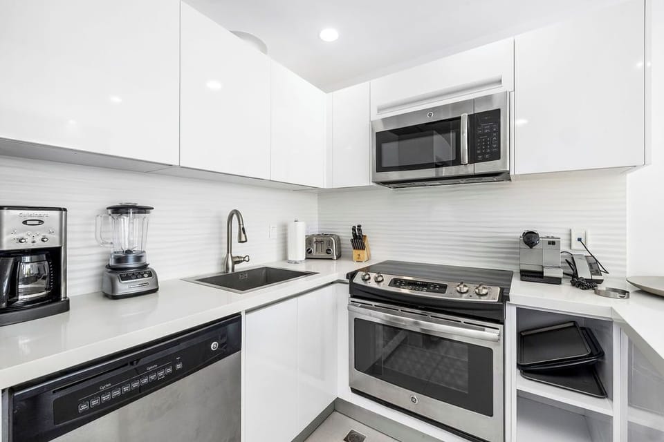 Your modern kitchen is outfitted with everything you need to whip up delicious meals—stainless steel appliances, a coffee maker, blender, and gleaming white countertops that make cooking a joy.
