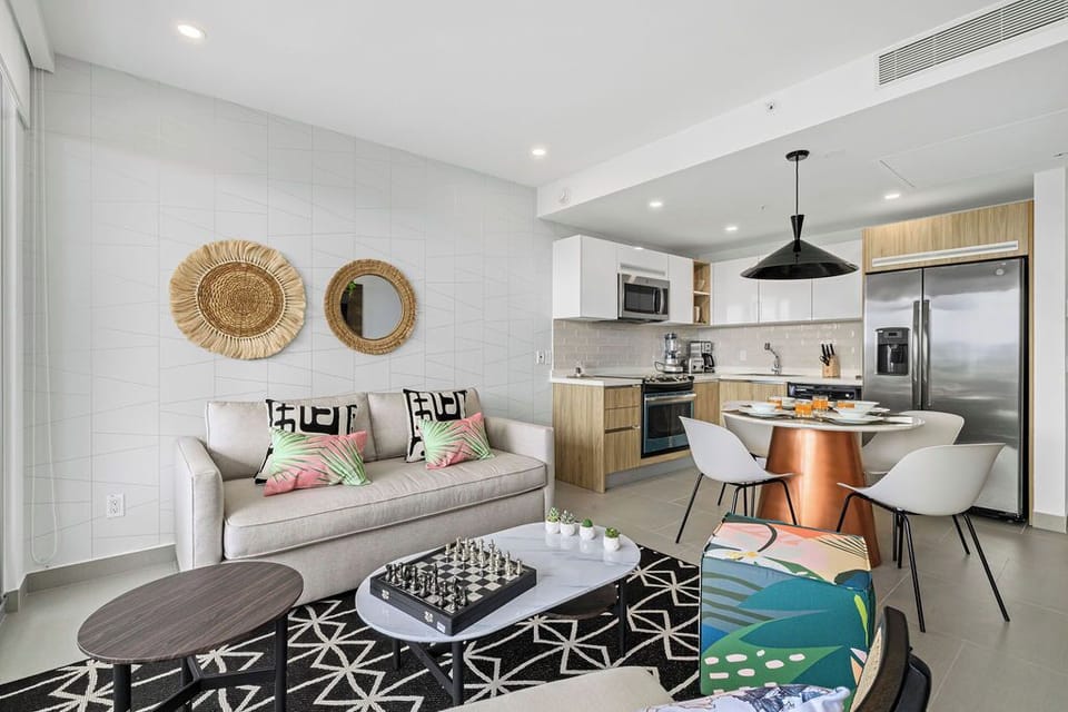 Unwind in your modern, open-concept space where coastal charm meets contemporary comfort. Relax on the sofa, gather at the dining table, and prepare meals with ease in your fully equipped kitchen.