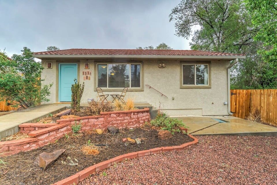 Welcoming single-story home with a wide driveway and a front yard finished in red gravel and curved brick planters. A mature tree and fenced side yard add greenery and privacy as you arrive and walk up the path to the front door.