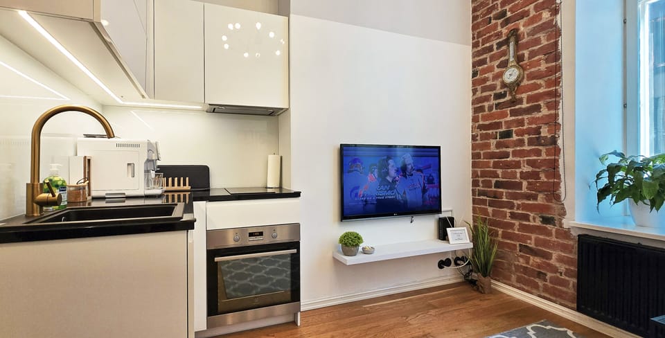 Style & entertainment: big TV, brick wall, compact modern kitchenette.