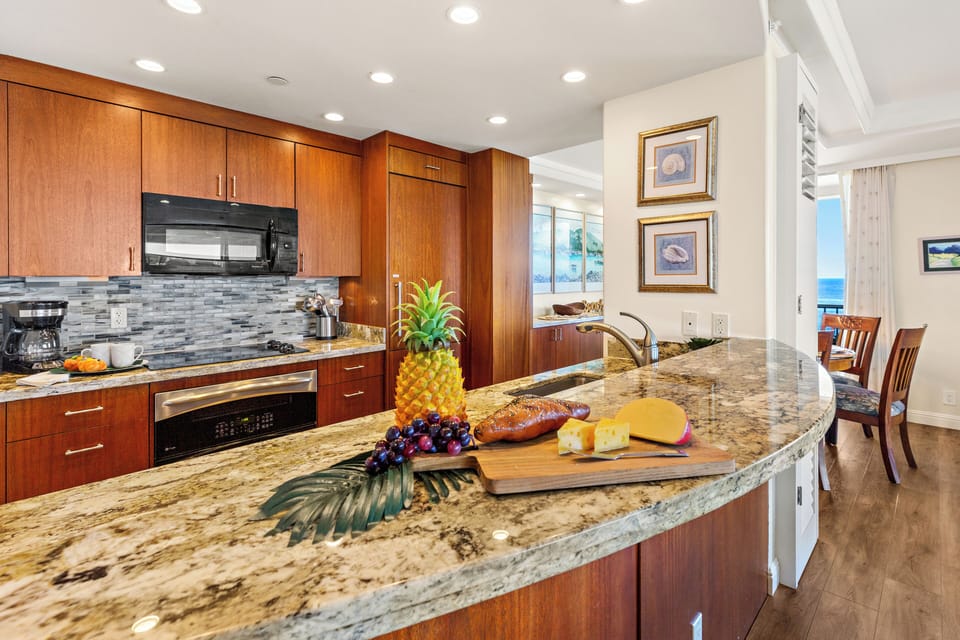 Well-appointed kitchen with sleek counters, wood finishes, and stainless accents. Bright, open layout enhances the space.