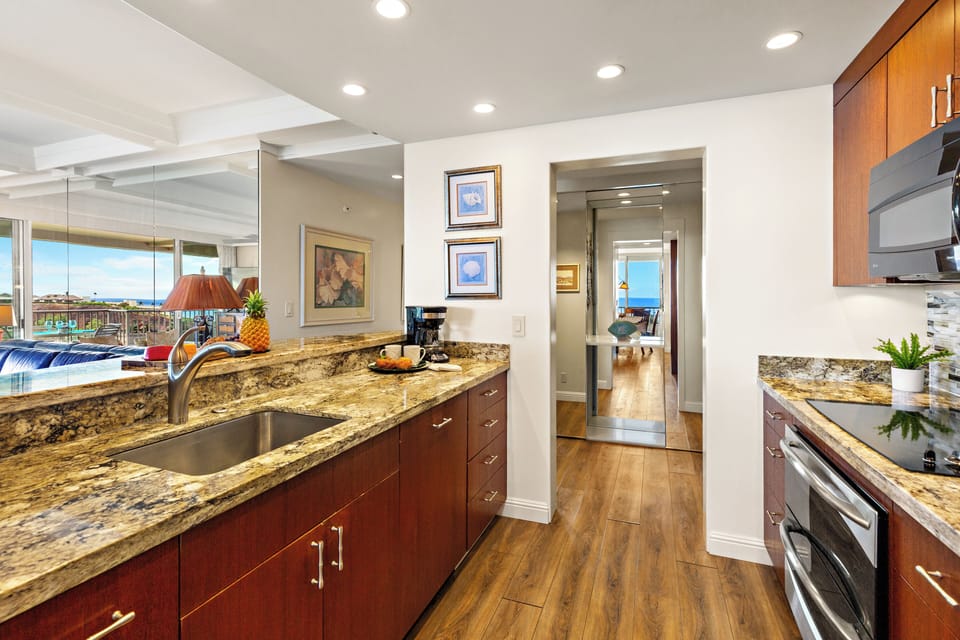 Well-appointed kitchen with sleek counters, wood finishes, and stainless accents. Bright, open layout enhances the space.