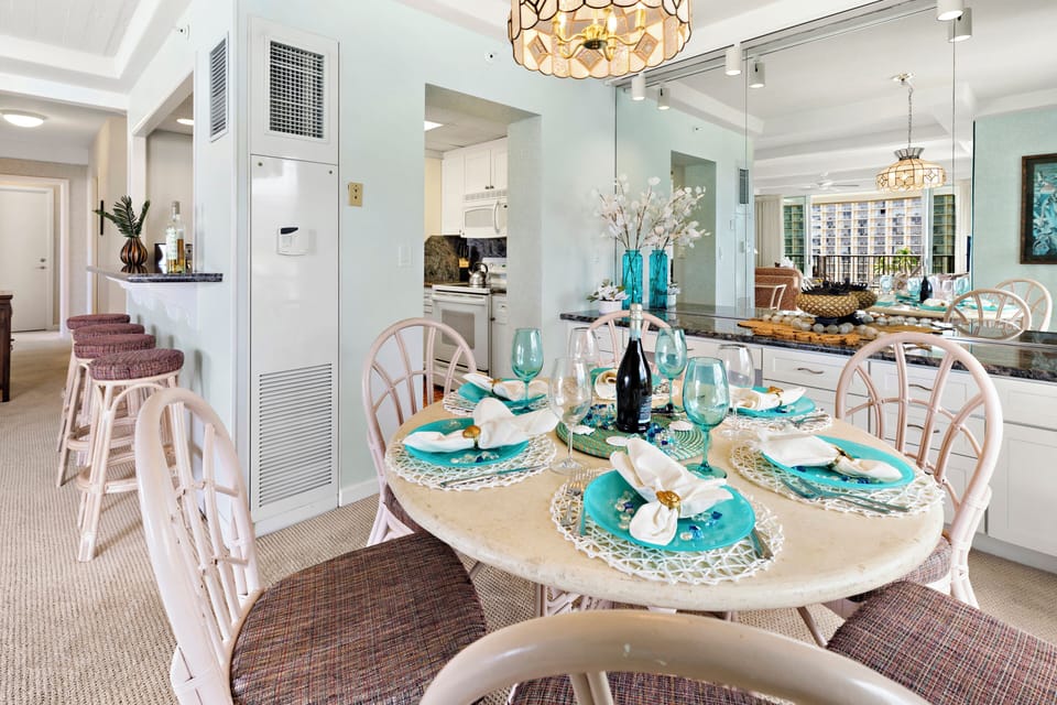 Styled dining table featuring coordinated place settings, glassware, and decorative accents beneath a statement chandelier.