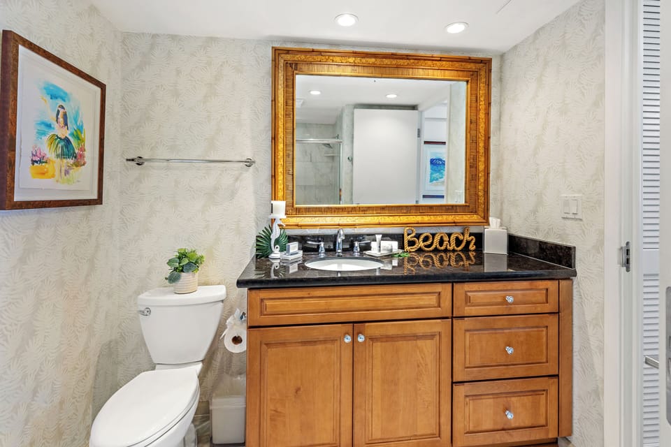 A beautifully appointed guest bathroom designed with comfort and convenience in mind. Featuring warm granite countertops, natural wood cabinetry, and soft, neutral tones, the space offers a clean and inviting atmosphere.