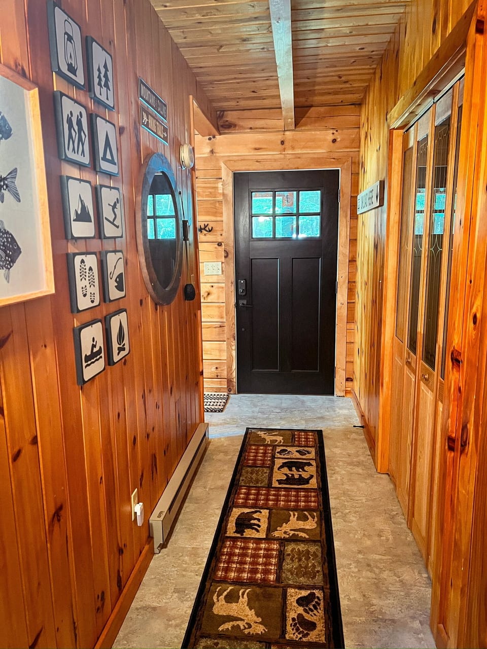 Step into the cabin and you’re greeted by a warm, wood-accented entry hall with rustic decor. This hallway leads to the downstairs bedrooms, bathroom, and the basement—home to the laundry area and a spacious open zone for lounging and play.