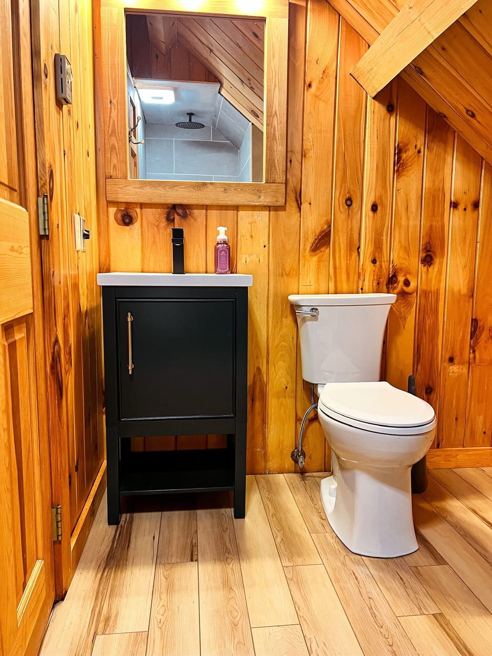 Upstairs bathroom with a walk-in shower and charming sloped ceilings—clean, bright, and full of cabin character.