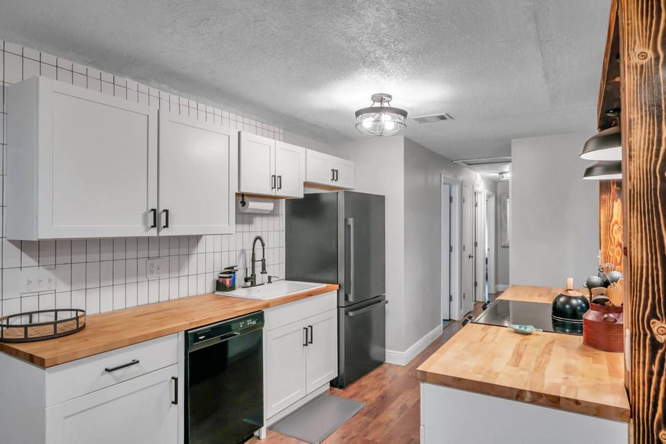 Fully Equipped Kitchen Offers Butcher Block Style Countertops, Sleek White Cabinets and Updated Appliances