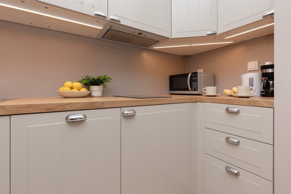 Another view of the kitchen, highlighting the clean countertops, ample storage, and minimalistic decor, maintaining a bright and functional space.