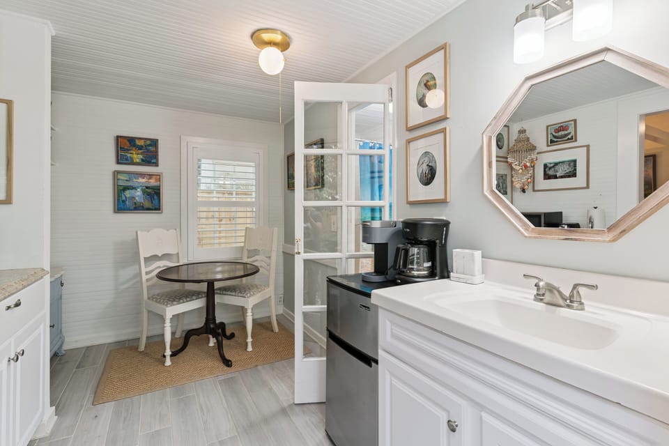 Thoughtful touches like a coffeemaker and mini-fridge make your morning routine effortless in this charming space with coastal artwork and natural light.