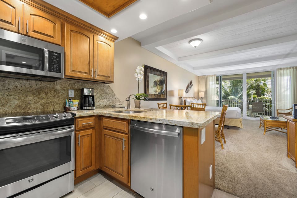 Your open-concept kitchen and living area flows seamlessly, featuring granite counters, stainless appliances, and a cozy dining space that opens to your private balcony with tropical views.