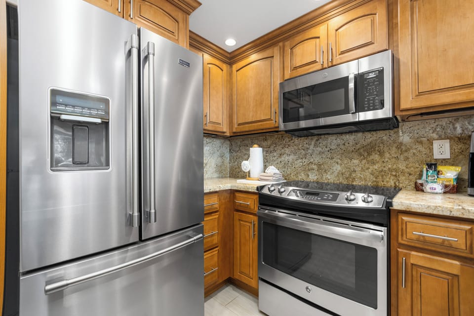 Your kitchen features stainless steel appliances, warm wood cabinetry, granite countertops, and a full-sized oven—ready for preparing memorable meals together during your stay.